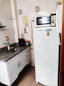 uma pequena cozinha com um micro-ondas em cima de um frigorífico em Apartamento completo no centro em Teresópolis
