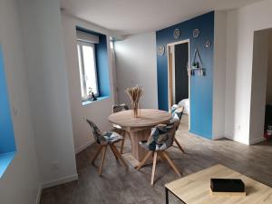 a dining room with a wooden table and chairs at Charmante maison tout confort in Noyelles-sous-Lens