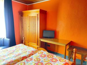 Schlafzimmer mit einem Bett und einem Schreibtisch mit einem TV in der Unterkunft Bartels Stadt-Hotel in Werl