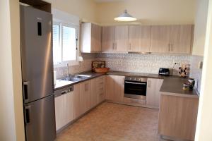 a kitchen with wooden cabinets and a stainless steel refrigerator at Hotel Stella in Volos