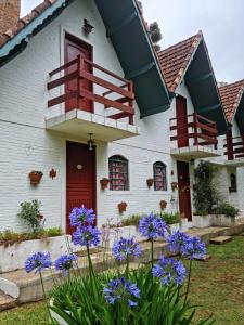 une maison blanche avec une porte rouge et des fleurs violettes dans l'établissement marcita chalé, à Monte Verde