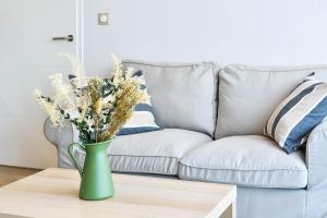 a green vase with flowers on a coffee table in front of a couch at OVELIA Toulouse - Les Bastides de Lardenne in Toulouse