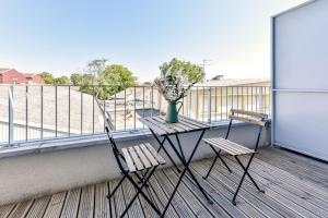 a balcony with two chairs and a table with flowers on it at OVELIA Toulouse - Les Bastides de Lardenne in Toulouse