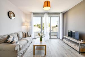 a living room with a couch and a tv at OVELIA Toulouse - Les Bastides de Lardenne in Toulouse