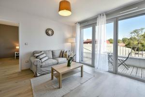 a living room with a couch and a large window at OVELIA Toulouse - Les Bastides de Lardenne in Toulouse