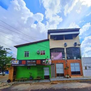 um edifício verde com bancos à sua frente em São Luís Hostel em São Luís