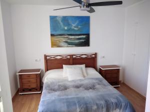 1 dormitorio con 1 cama con 2 mesitas de noche y una pintura en De la Montaña al Mar, en Almería