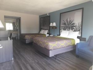 una habitación de hotel con 2 camas y una silla en Super 8 Motel by Wyndham near Fort Lauderdale Arpt, en Dania Beach