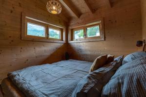 a bed in a log cabin with two windows at Holznest - dein Urlaub im gemütlichen Holzhaus in Schönau am Königssee