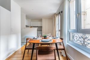 a dining room with a table and chairs and a window at Cozy flat Paris centre in Paris