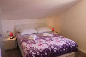 1 dormitorio con 1 cama morada y 2 toallas en Apartments Floki, en Cavtat