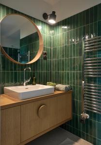 a green tiled bathroom with a sink and a mirror at NP2 Apartman in Bük