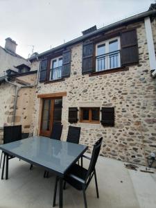 a table and chairs in front of a stone building at Les terrasses de Dordogne in Argentat