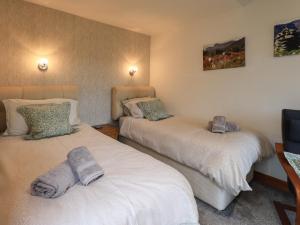 a bedroom with two beds with towels on them at Gale Lodge Cottage in Ambleside