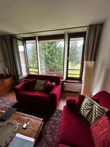 ein Wohnzimmer mit roten Möbeln und großen Fenstern in der Unterkunft [Campiglio] Appartamento Cristallo in Madonna di Campiglio