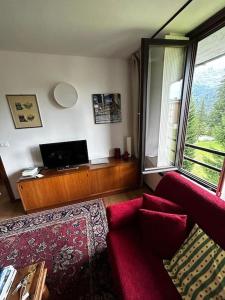 ein Wohnzimmer mit einem roten Sofa und einem Fenster in der Unterkunft [Campiglio] Appartamento Cristallo in Madonna di Campiglio