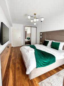 a bedroom with a large white bed with green sheets at Alegria Avantgarden Brasov in Braşov