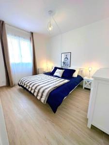 a bedroom with a bed with blue and white sheets at 7mn de Deauville Jardin Wifi Box TV in Saint-Arnoult