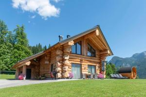 a log cabin in the mountains with green grass at Das Blockhaus Gosau - Your Austrian Home in Gosau