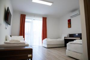 uma sala de estar com duas camas e uma janela em Rozmaring Apartmanház em Mórahalom