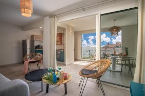 a living room with a table and chairs and a balcony at Kaouanne in Les Trois-Îlets