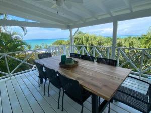 a wooden table and chairs on a deck with the ocean at Spectacular Cozy Sea View Staffed Villa in Las Terrenas