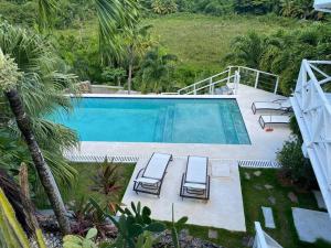 a swimming pool with two lounge chairs and a swimming pool at Spectacular Cozy Sea View Staffed Villa in Las Terrenas