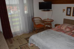 a bedroom with a bed and a table and a television at Penzion TOMI in Pribylina