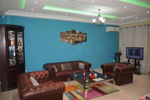 a living room with leather couches and a blue wall at Polgaro duplex luxueux in Douala