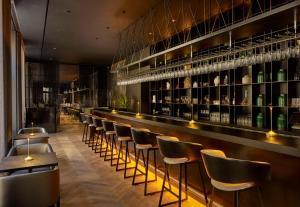 un bar con una fila di sgabelli e bottiglie di vino di art'otel Zagreb, Powered by Radisson Hotels a Zagabria