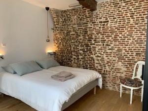 Ce lit se trouve dans une chambre dotée d'un mur en briques. dans l'établissement galerie jacqueline storme, à Lille