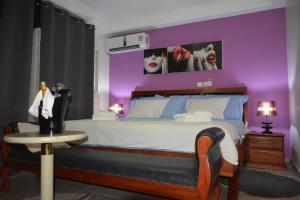 a bedroom with a large bed with purple walls at Polgaro duplex luxueux in Douala