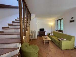 a living room with a green couch and stairs at Appartamenti Castagner in Pinzolo