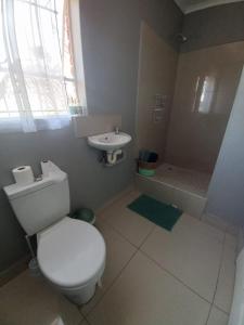 a white bathroom with a toilet and a sink at Rocky Hills Guesthouse in Piet Retief