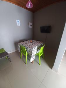 a table with green chairs in a room with a tv at Rocky Hills Guesthouse in Piet Retief