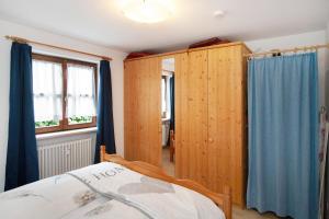Schlafzimmer mit Holzschränken und einem Bett mit blauen Vorhängen in der Unterkunft Ferienwohnung Reindler in Fischen im Allgäu