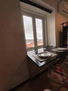 Cette chambre comprend une table avec deux verres et une fenêtre. dans l'établissement Apartamento t0 com vistas para o DOURO, à Vila Nova de Gaia