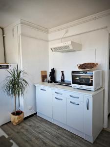 una cucina con mobili bianchi e un forno a microonde di Appartement entier, climatisé, vue mer ad Ajaccio