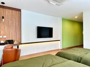 a bedroom with two beds and a tv on the wall at The Tangerine Guesthouse in Bangkok