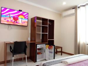 a room with a tv on a wall with a desk and a refrigerator at Hotel Chope Piesta in Santa Cruz de la Sierra