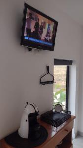 une télévision accrochée au mur avec un bureau et un ordinateur dans l'établissement Fioccohause, à Besanigo