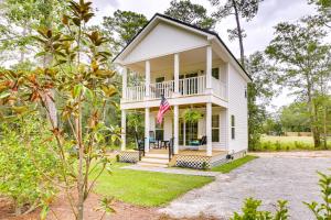 a white house with a porch and an american flag at Cozy Cottage Minutes to Downtown Southport! in Southport