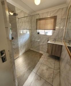 La salle de bains est pourvue d'une douche et d'un lavabo. dans l'établissement 29B Zebra Street - InHimwe Guesthouse, à Polokwane