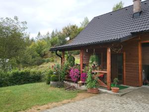 una cabina con fiori e piante di fronte ad essa di Chata Hriňová a Hriňová
