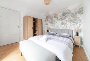 a white bedroom with a large white bed with blue pillows at Le Royal - Appartement design - Hyper centre in Vichy +26 photos