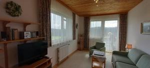 a living room with a couch and a tv and two windows at Ferienwohnung Kratochvil in Bernreith