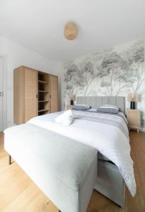 - une chambre dotée d'un grand lit blanc avec des arbres sur le mur dans l'établissement Le Royal - Appartement design - Hyper centre, à Vichy