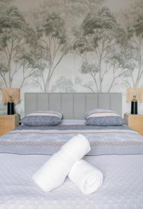 a bed with two white pillows and trees on the wall at Le Royal - Appartement design - Hyper centre in Vichy