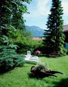 un jardín con un banco y una silla en el césped en Landhotel Herzogstand Garni en Kochel