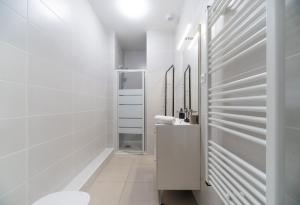 La salle de bains blanche est pourvue de toilettes et d'un lavabo. dans l'établissement Le Royal - Appartement design - Hyper centre, à Vichy